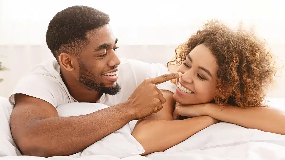 young black couple flirting laying on a bed